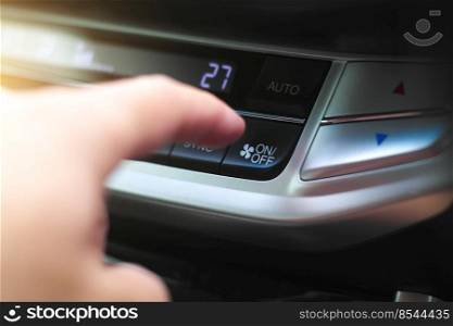 The driver hand is pressing the on-off button of the car air conditioner in the car.
