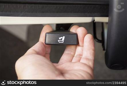 The driver hand is pulling on the car second seat folding button in the car trunk