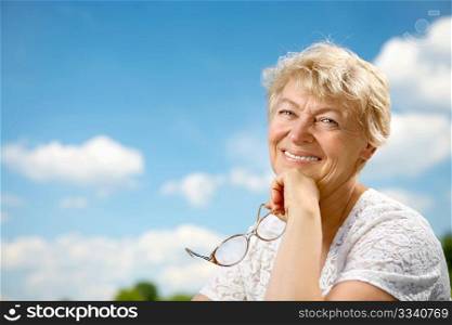 The elderly woman sits in a summer garden
