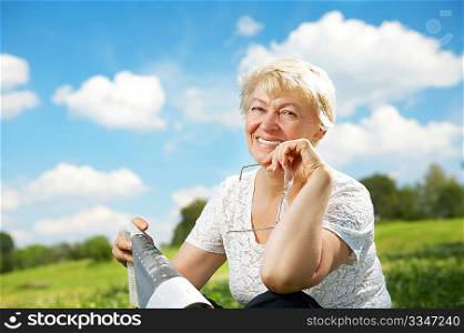 The elderly woman sits in a summer garden