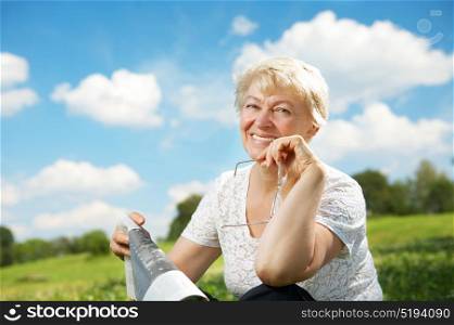 The elderly woman sits in a summer garden. The elderly lady