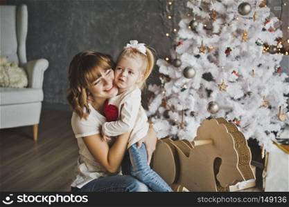 The embrace of a mother and daughter near the Christmas tree.. Mom hugging daughter at Christmas decorations 7101.