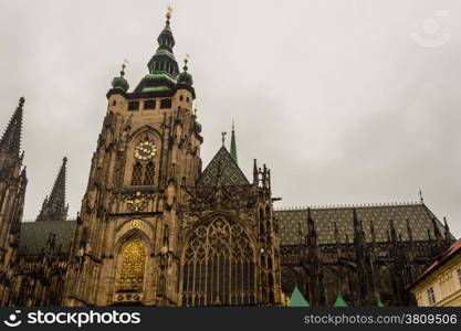 the exterior facade of the cathedral of St Vitus in Prague, a church with dark Gothic towers guarded by gargoyle: the main religious symbol of the Czech Republic in a cloudy and gloomy day