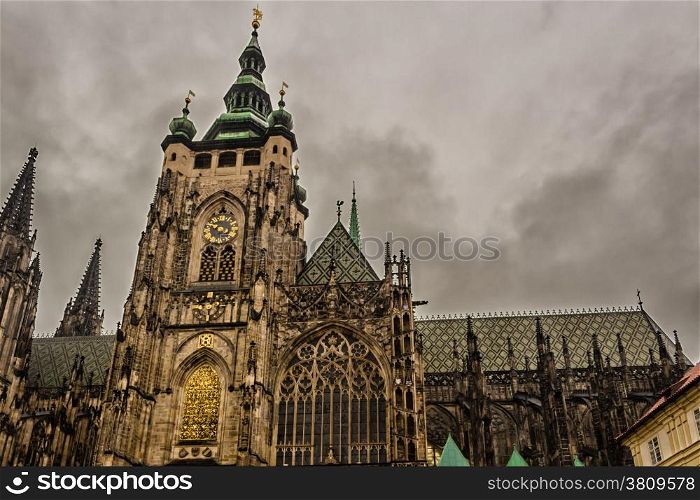 the exterior facade of the cathedral of St Vitus in Prague, a church with dark Gothic towers guarded by gargoyle: the main religious symbol of the Czech Republic in a cloudy and gloomy day