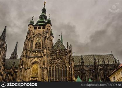 the exterior facade of the cathedral of St Vitus in Prague, a church with dark Gothic towers guarded by gargoyle: the main religious symbol of the Czech Republic in a cloudy and gloomy day