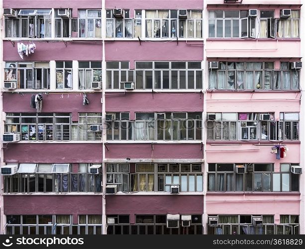 The exterior of an apartment building in Hong Kong shows several levels of flats. Laundry hangs from many of the apartments.