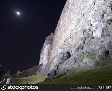 The exterior wall of Edinburgh Castle is built on a solid rock foundation. The fortifications of of heavy stones provide protection for the inner fortress. This long night exposure shows the moon with a bit of movement.