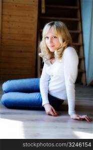 The fair-haired girl in jeans sits on a floor