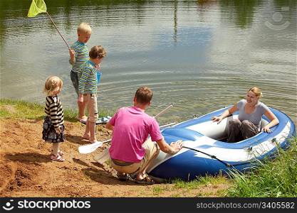 The family from five persons sits down in an inflatable boat