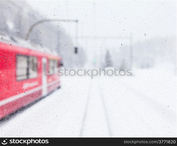 The famous Bernina red train, Unesco monument, in the middle of a winter storm