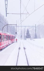 The famous Bernina red train, Unesco monument, in the middle of a winter storm