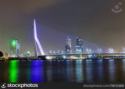 The famous Erasmus Suspension bridge with the Rotterdam skyline in the background at night, reflecting in the river Meuze