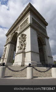 The famous landmark the Arc de Triomphe on the Champs Elisee in Paris seen through a wide angle, enhancing the perspective, from nearby, showing the sheer size of the monument