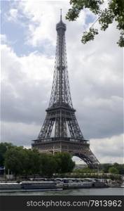 The famous landmark the Eiffel Tower seen from across the river Seine in paris, with the sun breaking through the clouds. The bus pariking is a tell tale for the masses who visit this world famous attraction