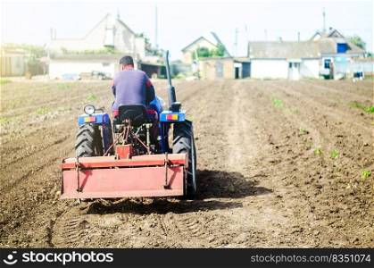 The farmer drives a tractor with a milling unit equipment. Loosening surface, land cultivation Use of agricultural machinery and to simplify and speed up work. Farming, agriculture. Plowing the field.