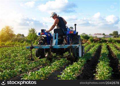 The farmer works in the field with a tractor. Agroindustry and agribusiness. Farming machinery. Plowing and loosening ground. Crop care, soil quality improvement. Farm field work cultivation.