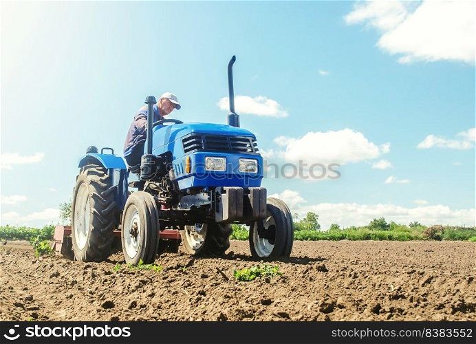 The farmer works on a tractor. Loosening the surface, cultivating the land for further planting. Grinding and loosening soil, removing plants roots from last harvest. Cultivation technology equipment.