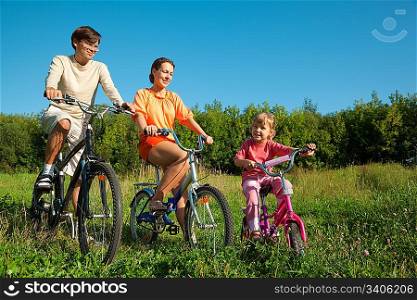 The father, mum and daughter go for a drive a sunny day on bicycles.