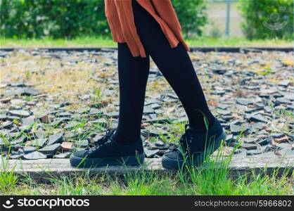 The feet and legs of a young woman as she is walking on some gravel