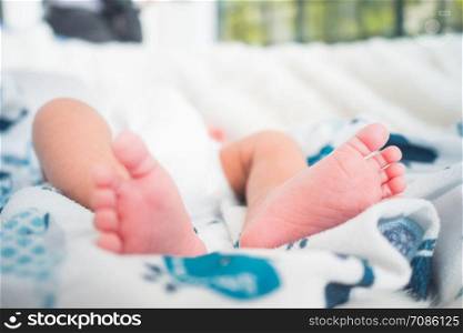 The feet of a new born child who is lying on a soft mattress