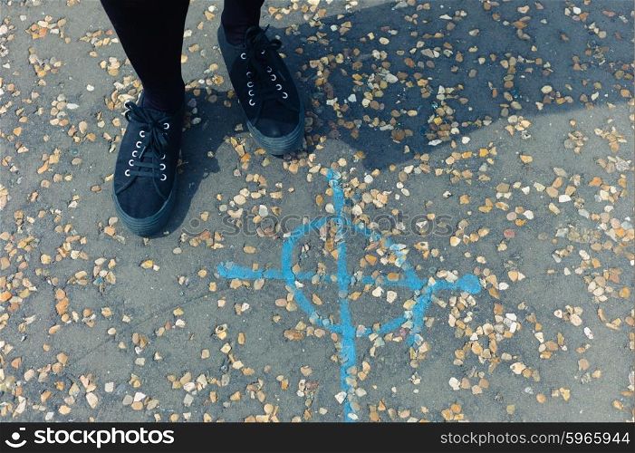 The feet of a woman standing outside by a road marking