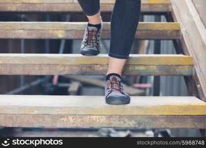 The feet of a young woman as she is walking down some wooden steps