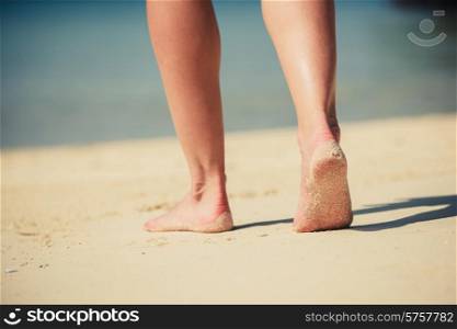 The feet of a young woman as she is walking on the beach