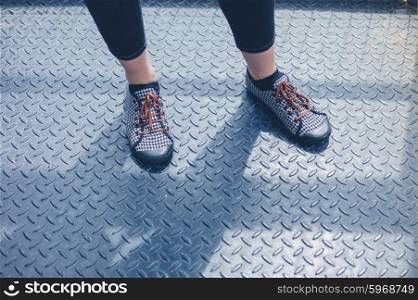 The feet of a young woman standing on a metal surface
