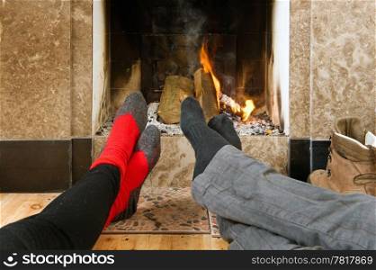 The feet of two hikers warming up by the fire after a long hike on a winter&rsquo;s day