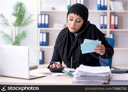 The female employee bookkeeper in hijab working in the office. Female employee bookkeeper in hijab working in the office
