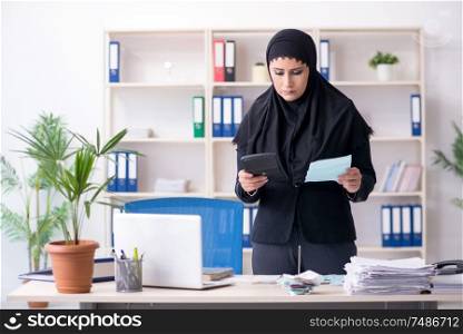 The female employee bookkeeper in hijab working in the office . Female employee bookkeeper in hijab working in the office