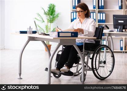 The female employee in wheel-chair at the office . Female employee in wheel-chair at the office