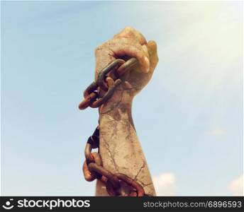 the female hand is wrapped in an iron rusty chain and raised up in the sun&rsquo;s rays against the sky