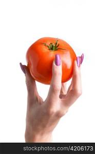 The female hand with long nails with manicure holds a tomato