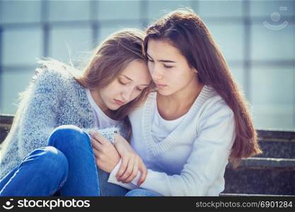 The Female Teen is Crying because of Teenage Problems, and Her Friend Looks Sympathetically at Her, Sitting on the Stairs