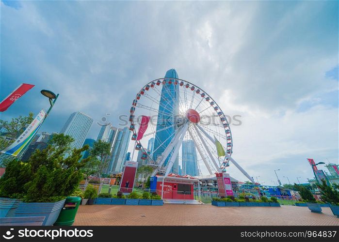 The ferris wheel, Hong Kong Observation Wheel, and amusement park for kids in holiday vacation and travel trip concept. Hong Kong City. Downtown and Victoria Harbour with blue sky.