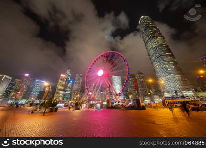 The ferris wheel, Hong Kong Observation Wheel at night, and amusement park for kids in holiday vacation and travel trip concept. Hong Kong City. Downtown and Victoria Harbour.