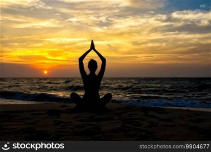 The figure of a girl on the background of the sea and sunset in a yoga pose on one leg.. figure of a girl on the background of the sea