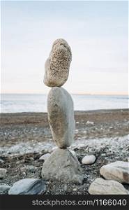 The figure of stones standing on each other, on the beach against the sea.