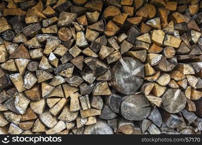 The firewood is packed in a woodpile for the winter season