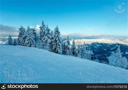 The first shadows of setting sun on winter mountain slopes with ski run (Skole Beskids, Lviv Oblast, Carpathians, Ukraine)