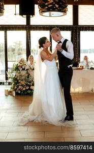 the first wedding dance of the bride and groom inside the restaurant hall in sunset light