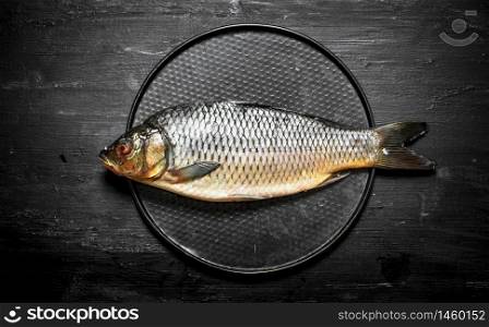 The fish on the plate. On a black wooden background.. The fish on the plate.