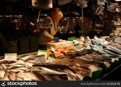 The fish seller in a fish section of the market is cutting a fish with a knife. No visible faces, logos or TM&rsquo;s, quite ready for commercial use.