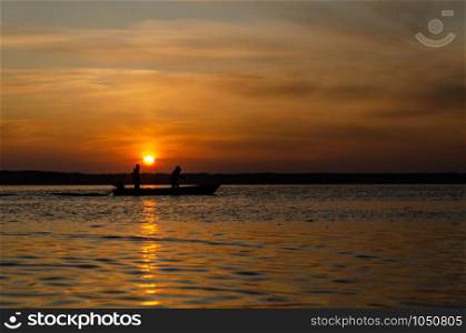 The fishermen and boat silhouette on the lake.