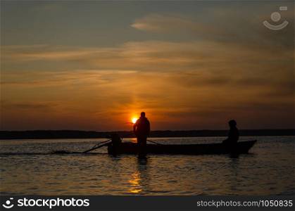 The fishermen and boat silhouette on the lake in sunrise.