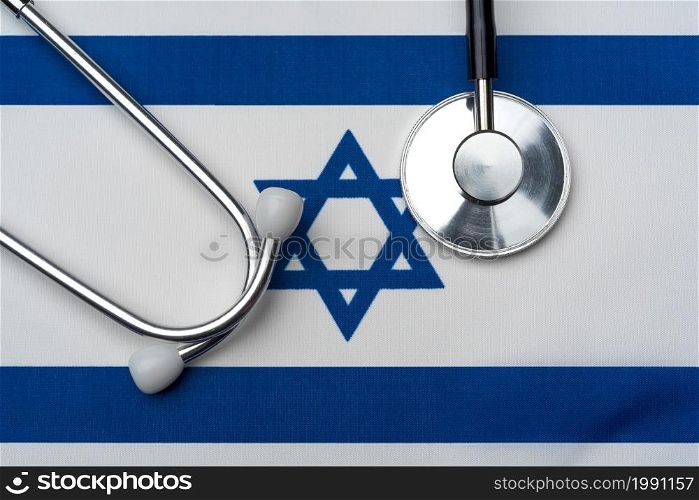 The flag of Israel and a stethoscope. The concept of medicine. Stethoscope on the flag in the background.. The flag of Israel and a stethoscope. The concept of medicine.