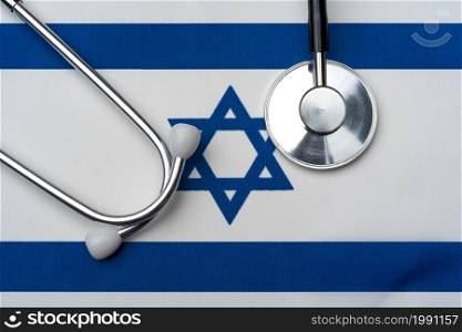 The flag of Israel and a stethoscope. The concept of medicine. Stethoscope on the flag in the background.. The flag of Israel and a stethoscope. The concept of medicine.