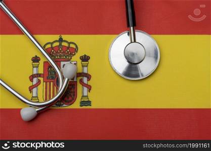 The flag of Spain and a stethoscope. The concept of medicine. Stethoscope on the flag in the background.. The flag of Spain and a stethoscope. The concept of medicine.