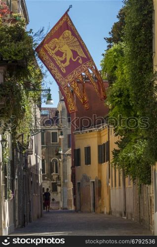 The flag of Venice in a quite street in Venice, Italy. The flag of the Italian region of Veneto historically used by the Republic of Venice from as early as 697AD.